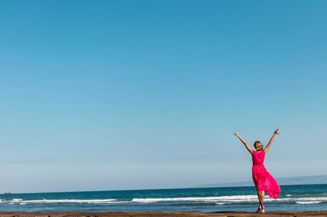 una mujer con un vestido rojo de pie en la costa