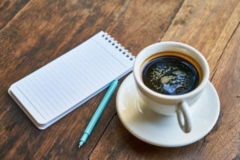 taza de café, bloc de notas, bolígrafo