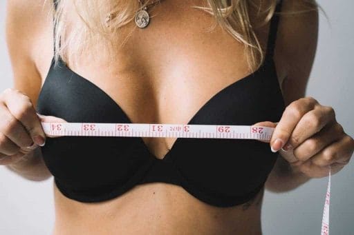 una mujer se mide los pechos con un centímetro