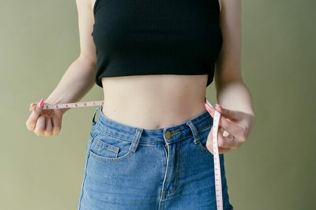  una mujer se mide la cintura con un centímetro