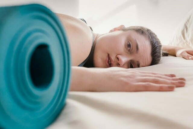  mujer agotada por el entrenamiento, junto a la colchoneta de ejercicios