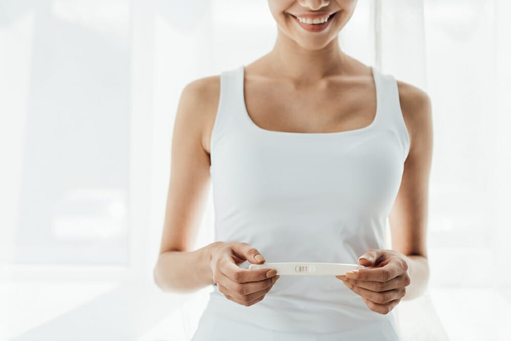  una mujer satisfecha sostiene un test de embarazo positivo