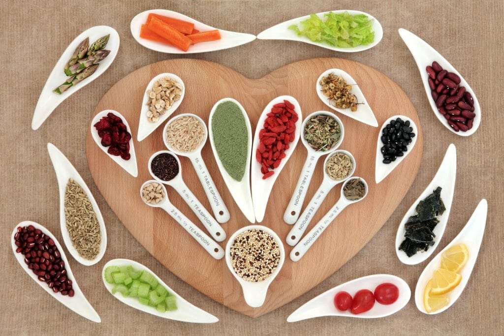  Hierbas y otros productos saludables sobre una tabla de cortar en forma de corazón