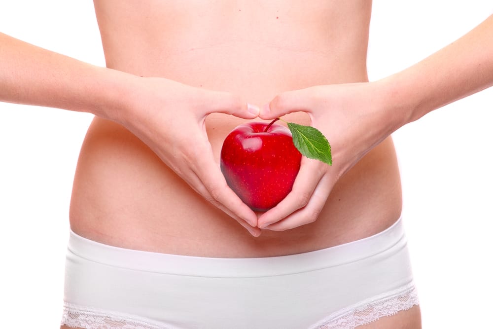  una mujer se lleva una manzana al estómago